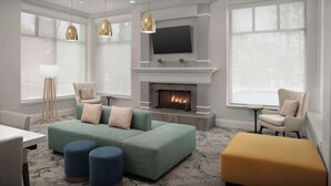 Una sala de estar moderna con chimenea, asientos cómodos y un televisor de pantalla plana montado sobre ella.