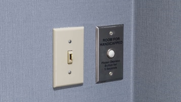 Un interruptor y un botón con la etiqueta 'ROOM FOR HANDICAPPED' con instrucciones para mantener presionado el botón durante 5 segundos.