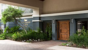 La entrada de un edificio con una puerta de madera, un letrero que dice 'Homewood Suites' y un camino de ladrillos que conduce a la entrada.