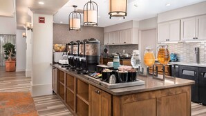 Eine moderne Küche mit einer zentralen Kochinsel, einer Kaffeestation und einem Getränkespender.