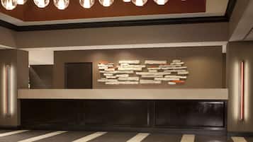 A reception area with a modern design, featuring a stone wall art installation and a long reception desk.