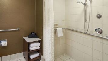 A shower area with a glass door, a towel rack, and a shelf with towels.