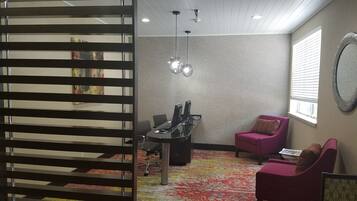 A modern office space with a desk, chairs, a patterned carpet, and a decorative mirror.