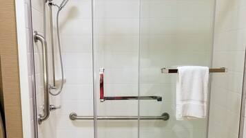 A glass-enclosed shower stall with a handrail, a towel rack, and a glass door.