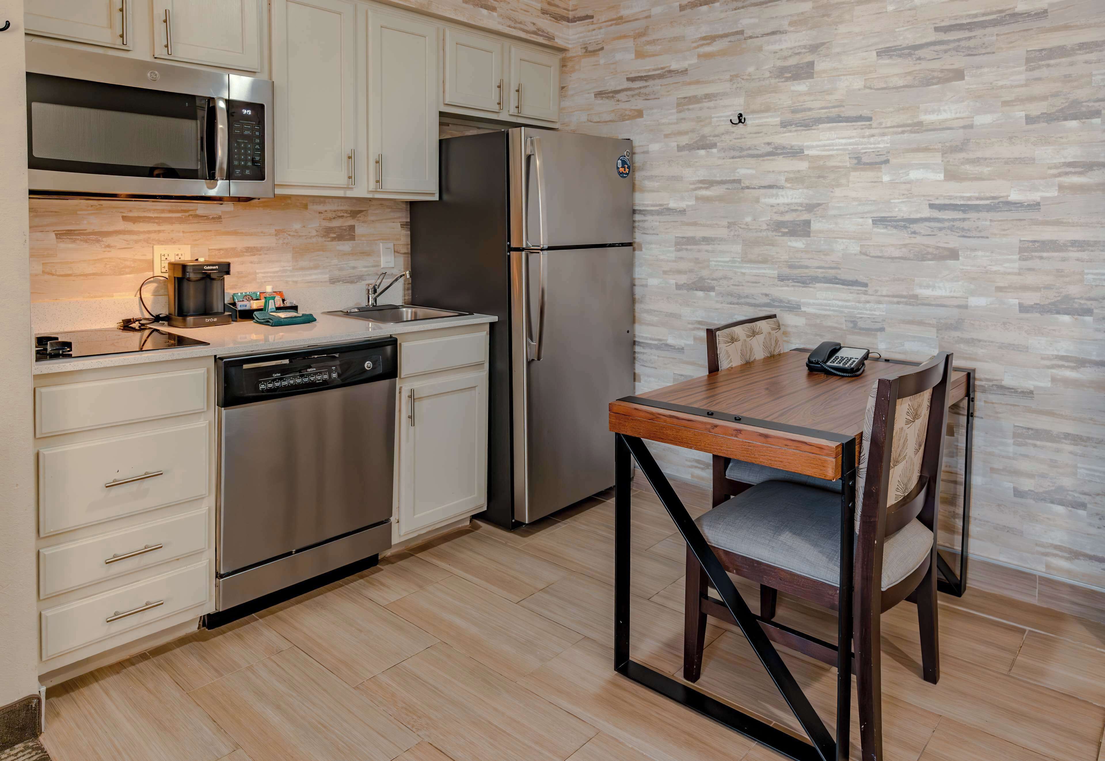 Una cocina moderna con electrodomésticos de acero inoxidable, lavavajillas y salpicadero con diseño de piedra.