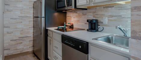 A modern kitchen with stainless steel appliances, a dishwasher, a microwave, and a coffee maker.