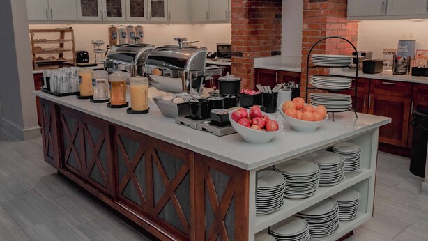 Una cocina moderna con una isla central, electrodomésticos integrados y una pared de ladrillo.