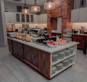 A modern kitchen with a central island, built-in appliances, and a brick wall. - Homewood Suites by Hilton Ft. Worth-Bedford (Bedford)