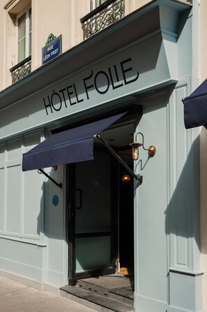 A hotel entrance with a sign reading "Hôtel Folle" and a blue awning. - Hôtel Folie – Orso Hotels (Paris)