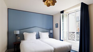 A hotel room with a large bed, a nightstand, a lamp, a ceiling fan, and a view of the outside balcony. - Hôtel Folie – Orso Hotels (Paris)