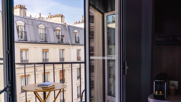 A balcony with a table and chair, a book, and a coffee machine. - Hôtel Folie – Orso Hotels (Paris)