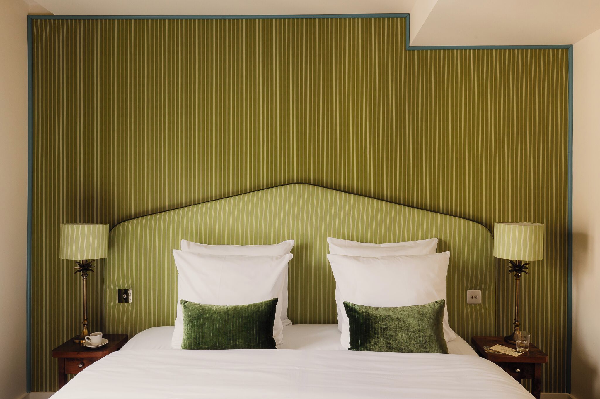 A hotel room with a large bed, two bedside tables, and green-striped wallpaper.