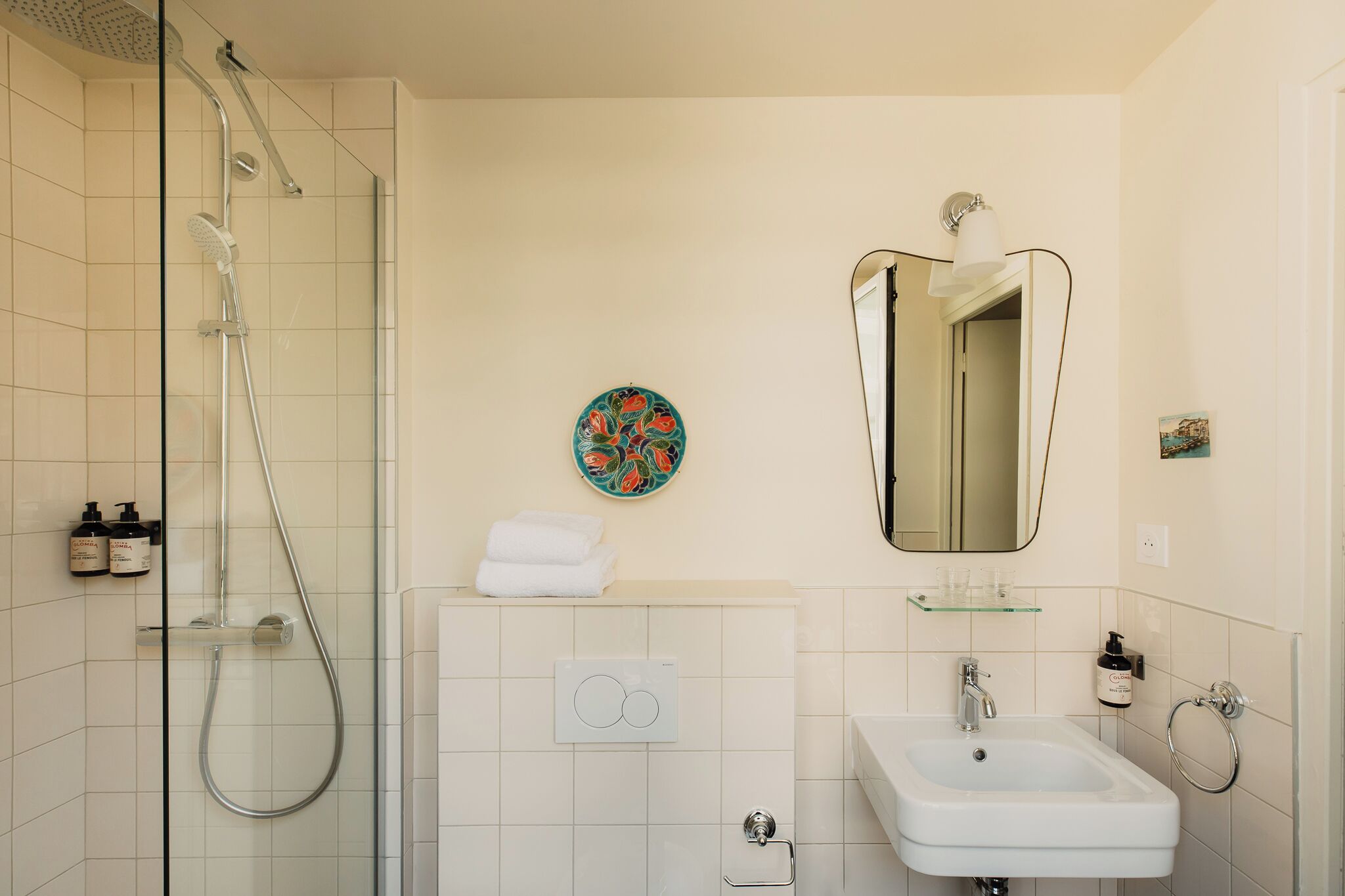 Une salle de bain moderne avec une douche à parois de verre, un lavabo blanc et un grand miroir.