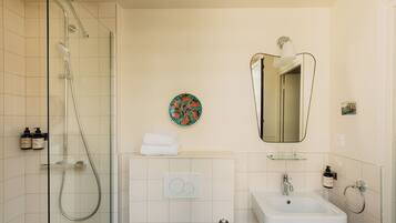 Une salle de bain moderne avec une douche à parois de verre, un lavabo blanc et un grand miroir.