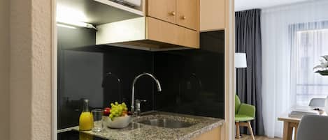 A modern kitchen with granite countertops, a stainless steel sink, and wooden cabinets.
