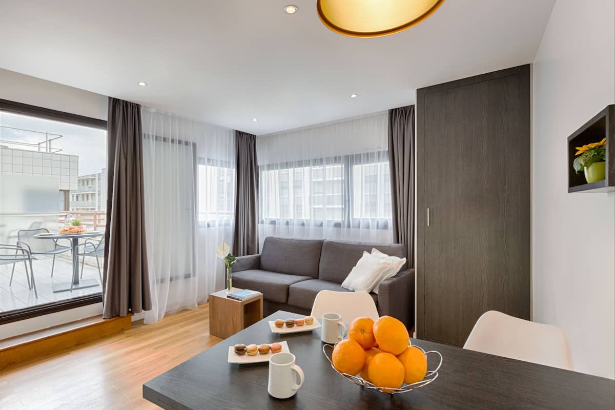 Un salon moderne avec un canapé, une table à manger et une vue sur la ville.