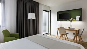 A hotel room with a large bed, a desk with two chairs, a TV on the wall, and a window with curtains. - Citadines Austerlitz Paris (Paris)