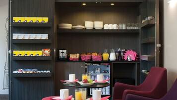 Una mesa con sillas y estantes llenos de platos, tazones, tazas y alimentos para el desayuno.