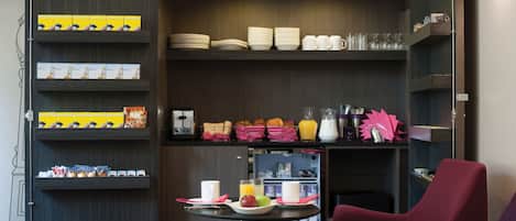 Una mesa con sillas y estantes llenos de platos, tazones, tazas y alimentos para el desayuno.