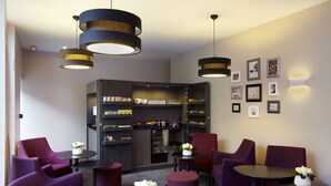 A modern lounge area with purple seating, a coffee station, and a bookshelf with various items. - Citadines Austerlitz Paris (Paris)
