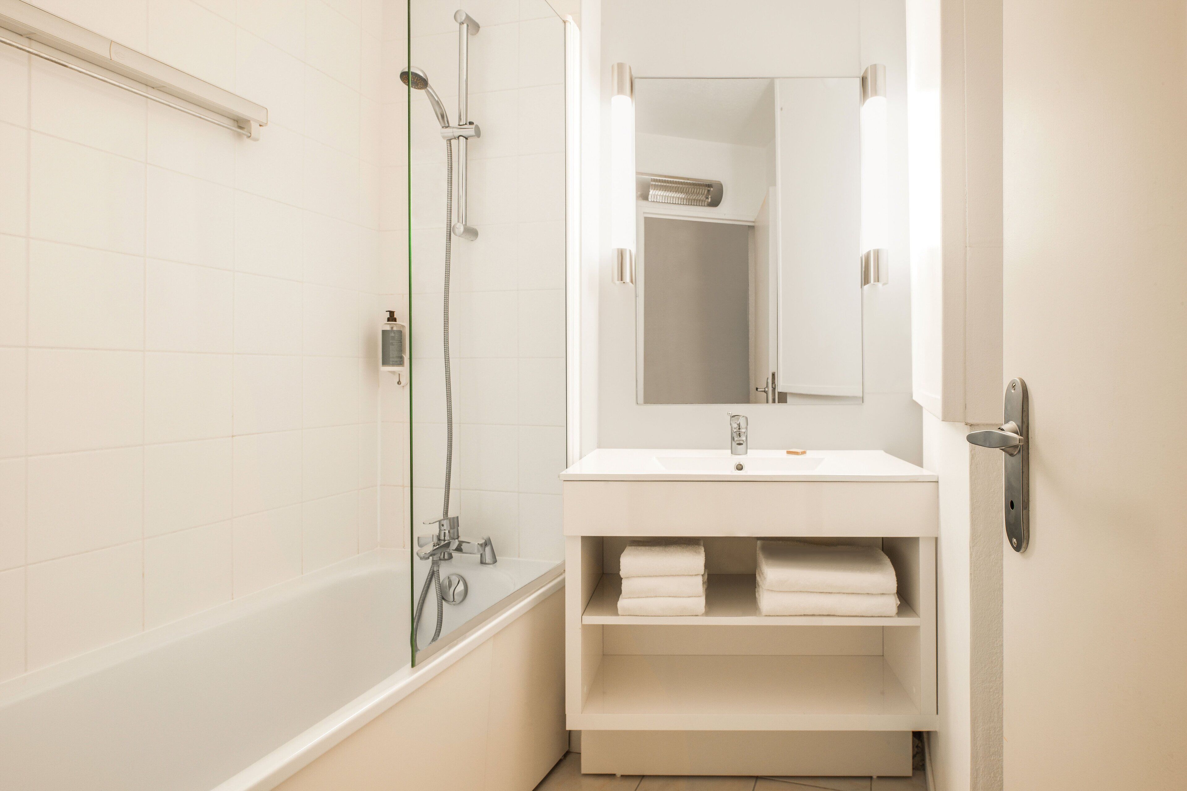 A modern bathroom with a bathtub, shower, and a vanity with a mirror.