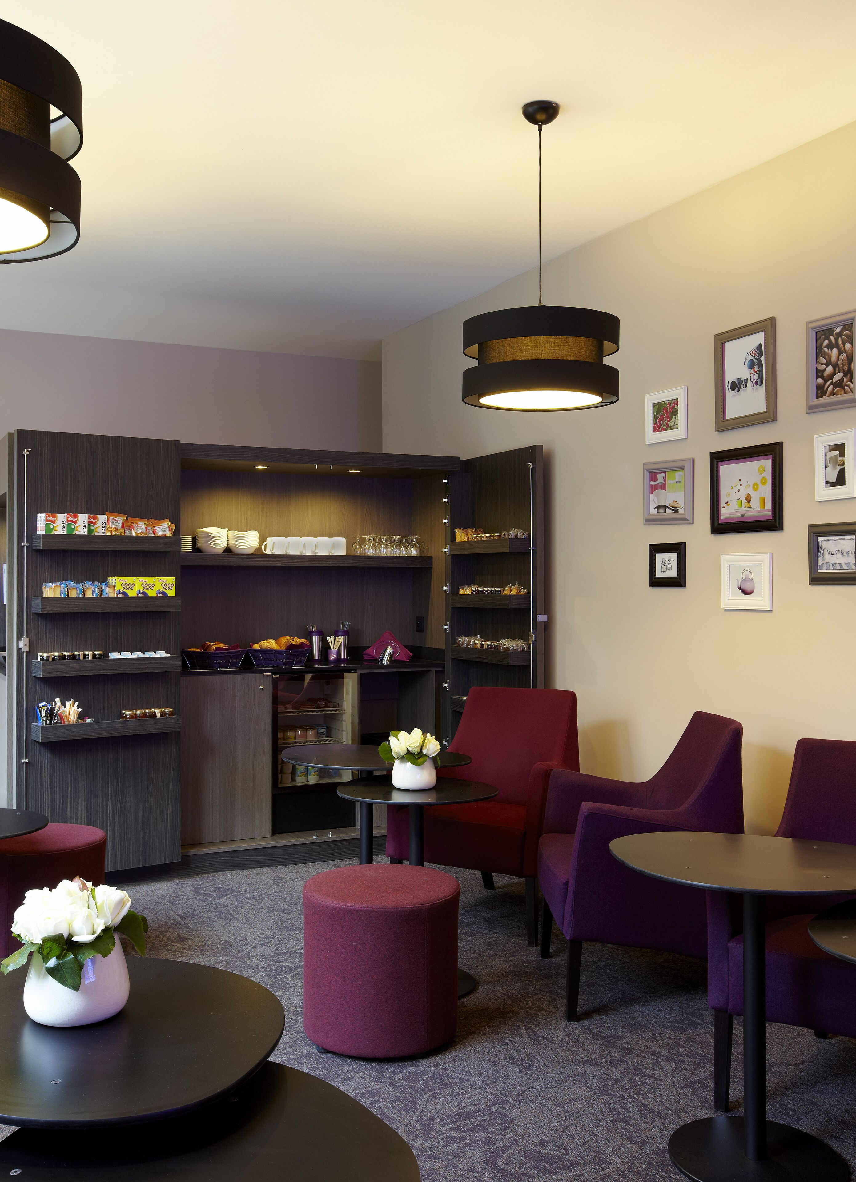 A modern lounge area with seating, a coffee station, and wall art.