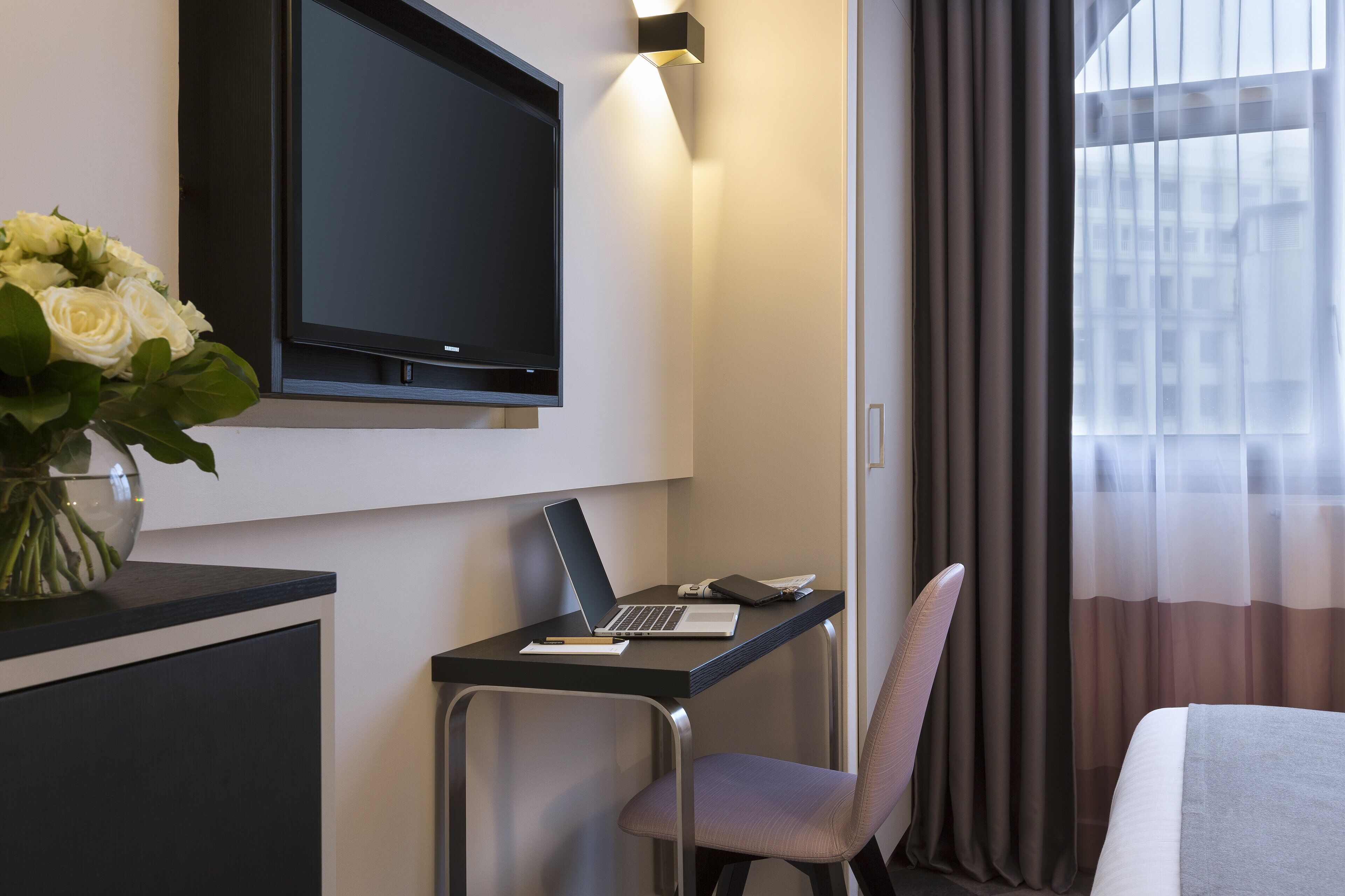 Una habitación de hotel con escritorio, computadora portátil y televisor.