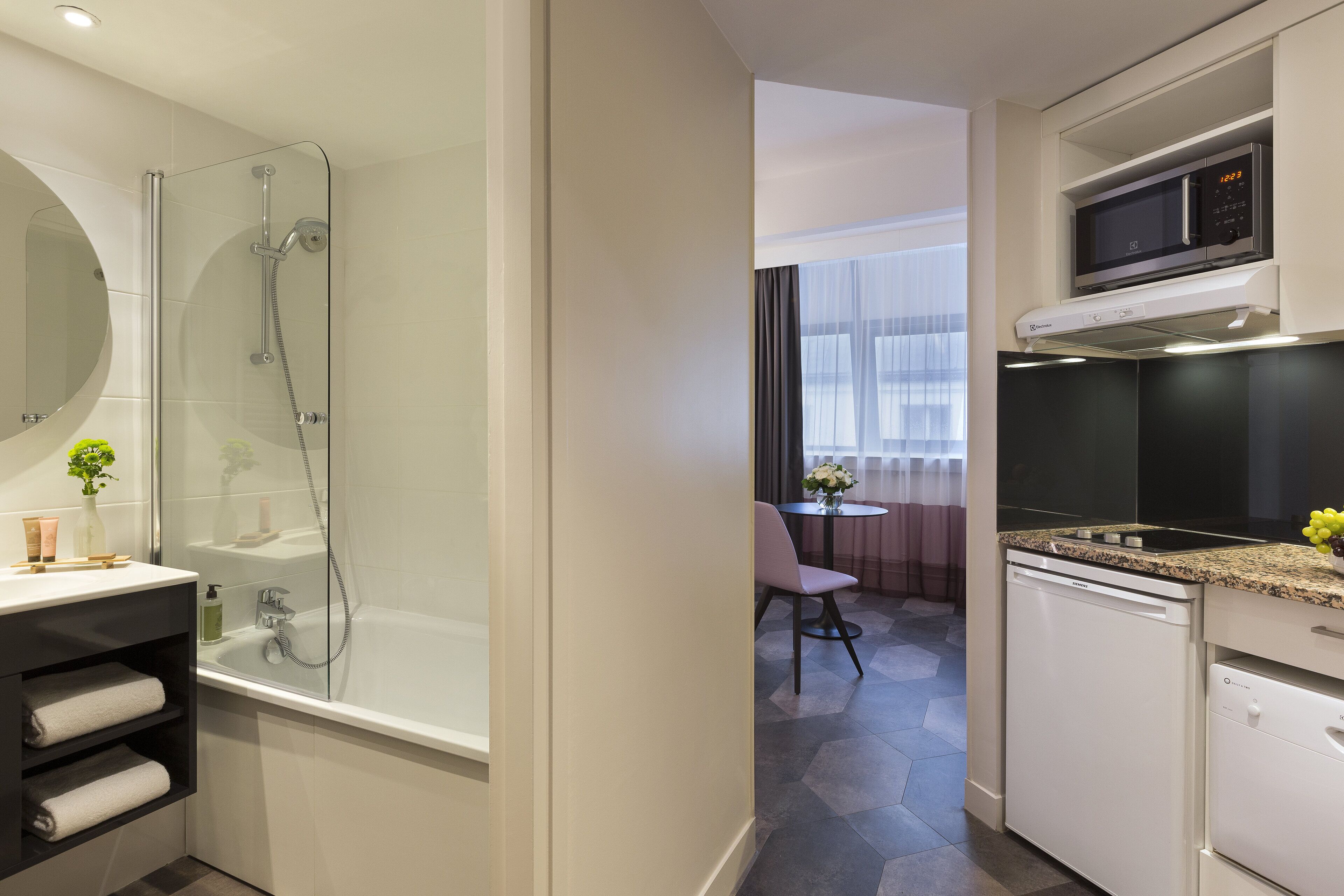 Un bagno moderno con cabina doccia in vetro, lavandino bianco e forno a microonde integrato sopra il piano di lavoro.