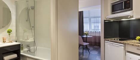 A modern bathroom with a glass-enclosed shower, a white sink, and a built-in microwave above the countertop.