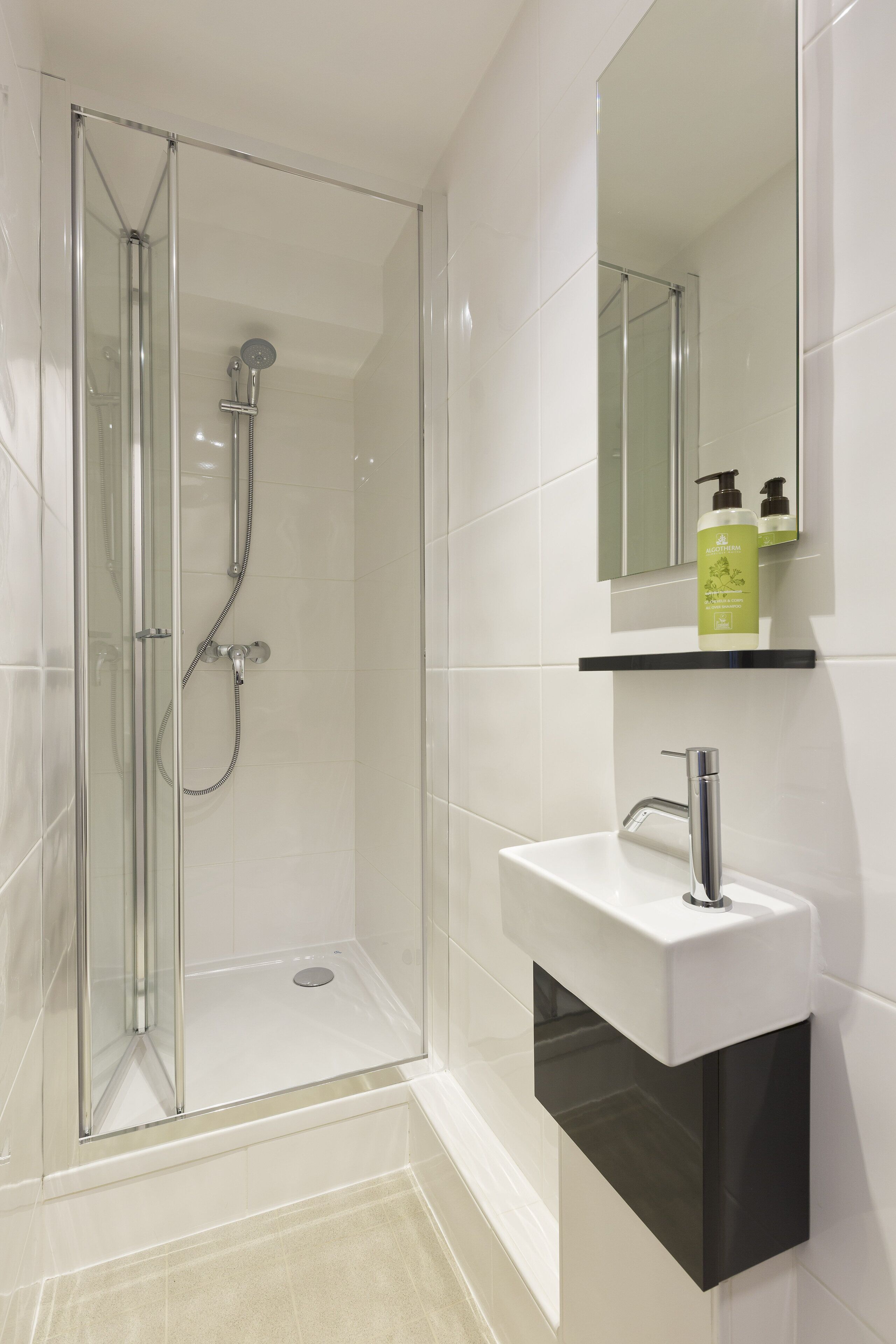 A modern bathroom with a glass-enclosed shower, a white sink, and a mirror above it.