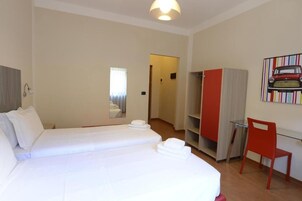 Una camera d'albergo con un letto grande, una scrivania, una sedia, un armadio e uno specchio.