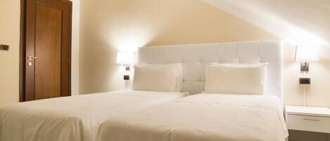 A bedroom with a large bed, two bedside tables, and a wooden door.