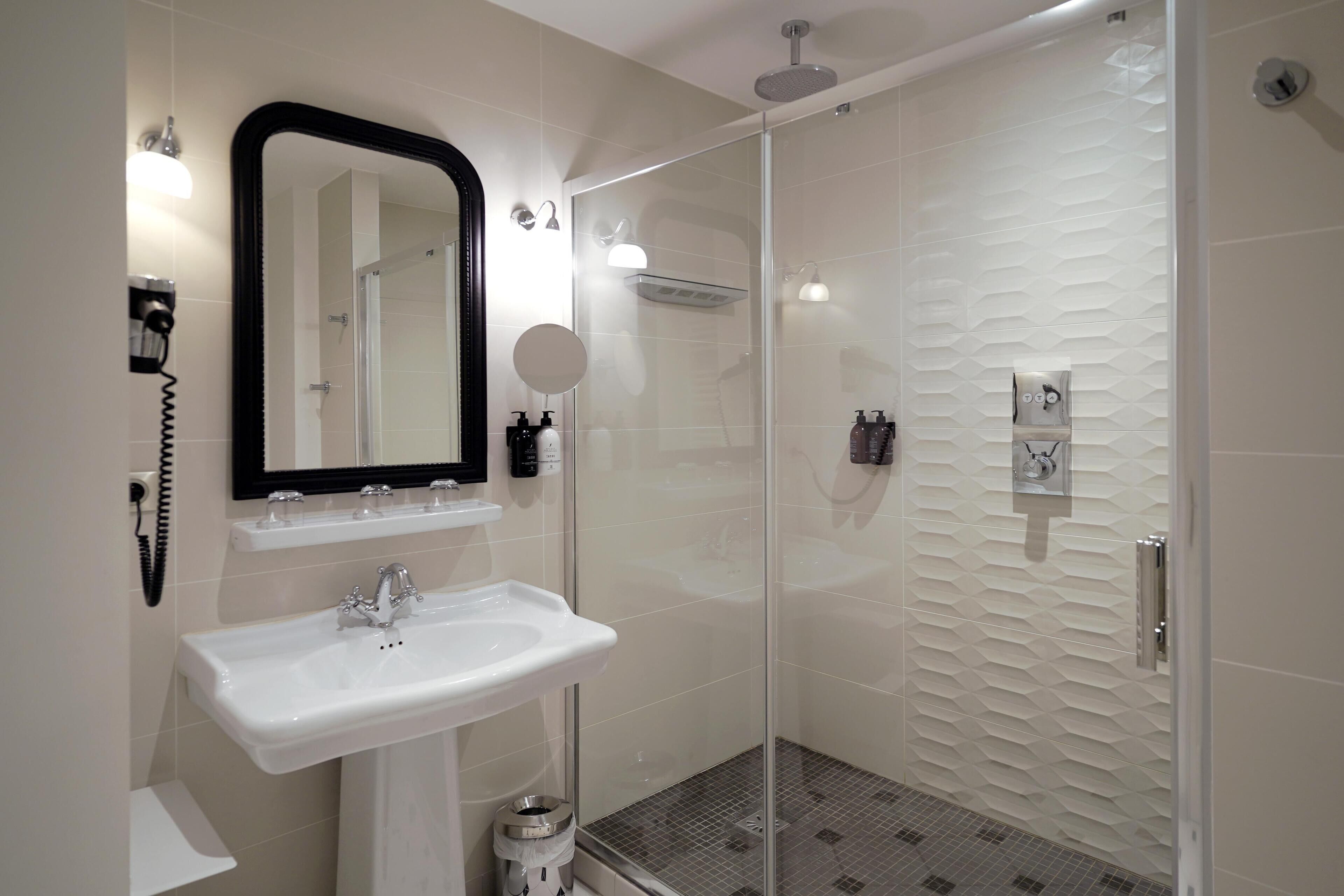 A modern bathroom with a glass-enclosed shower, a white sink, and a mirror.