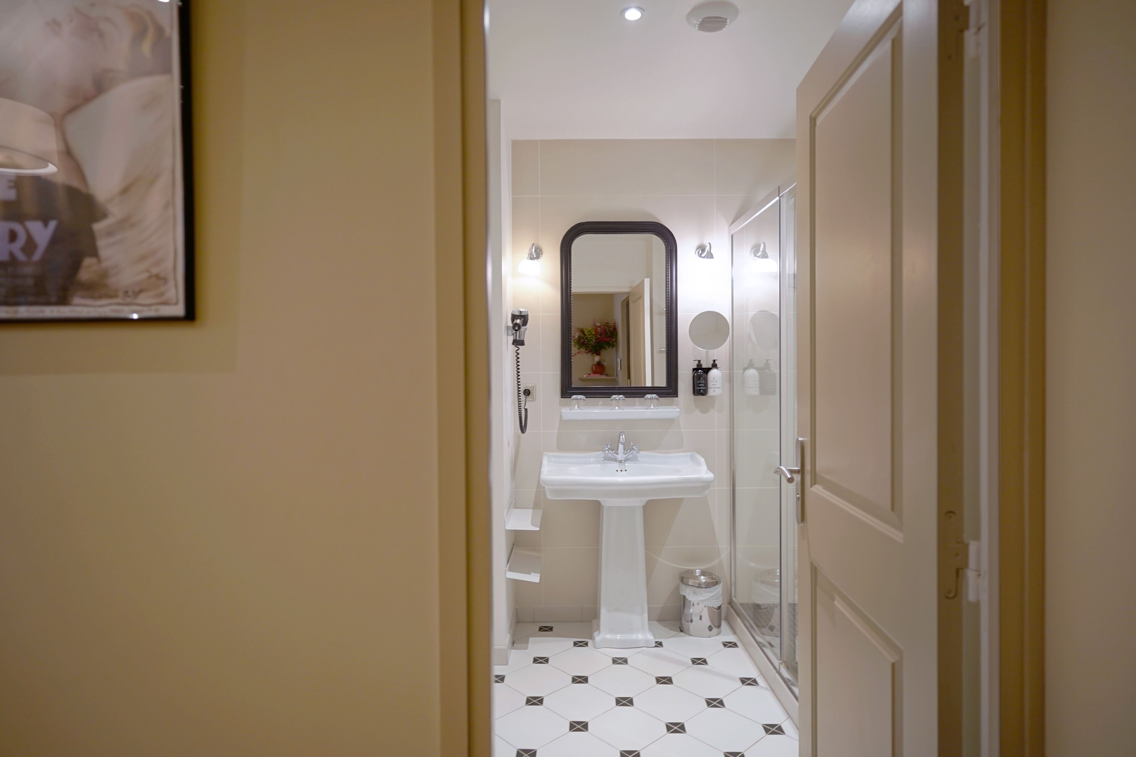 Een badkamer met een wastafel op een zuil, een spiegel en een toilet.
