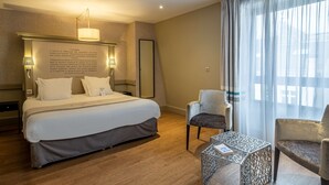 Een hotelkamer met een groot bed, twee bedlampen, een tafeltje en een stoel.