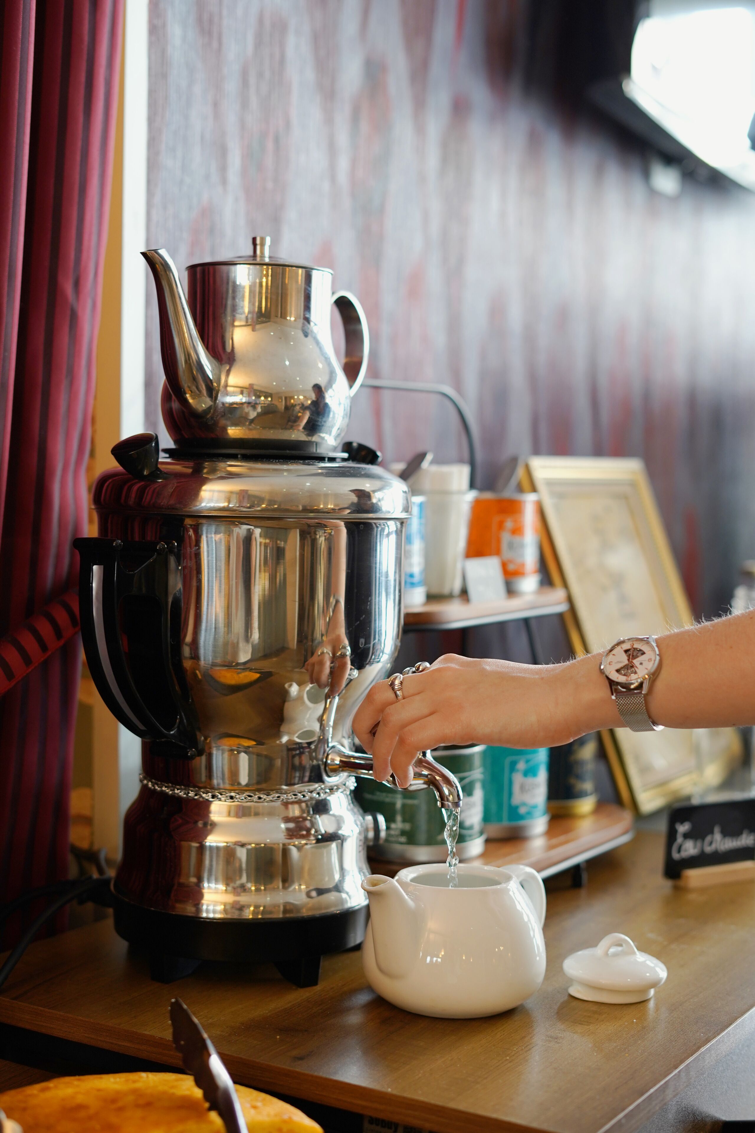 A person pouring water into a teapot on a wooden table.