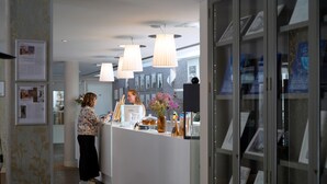 Een receptie met een balie, ingekaderde foto's aan de muur en een glazen vitrine.