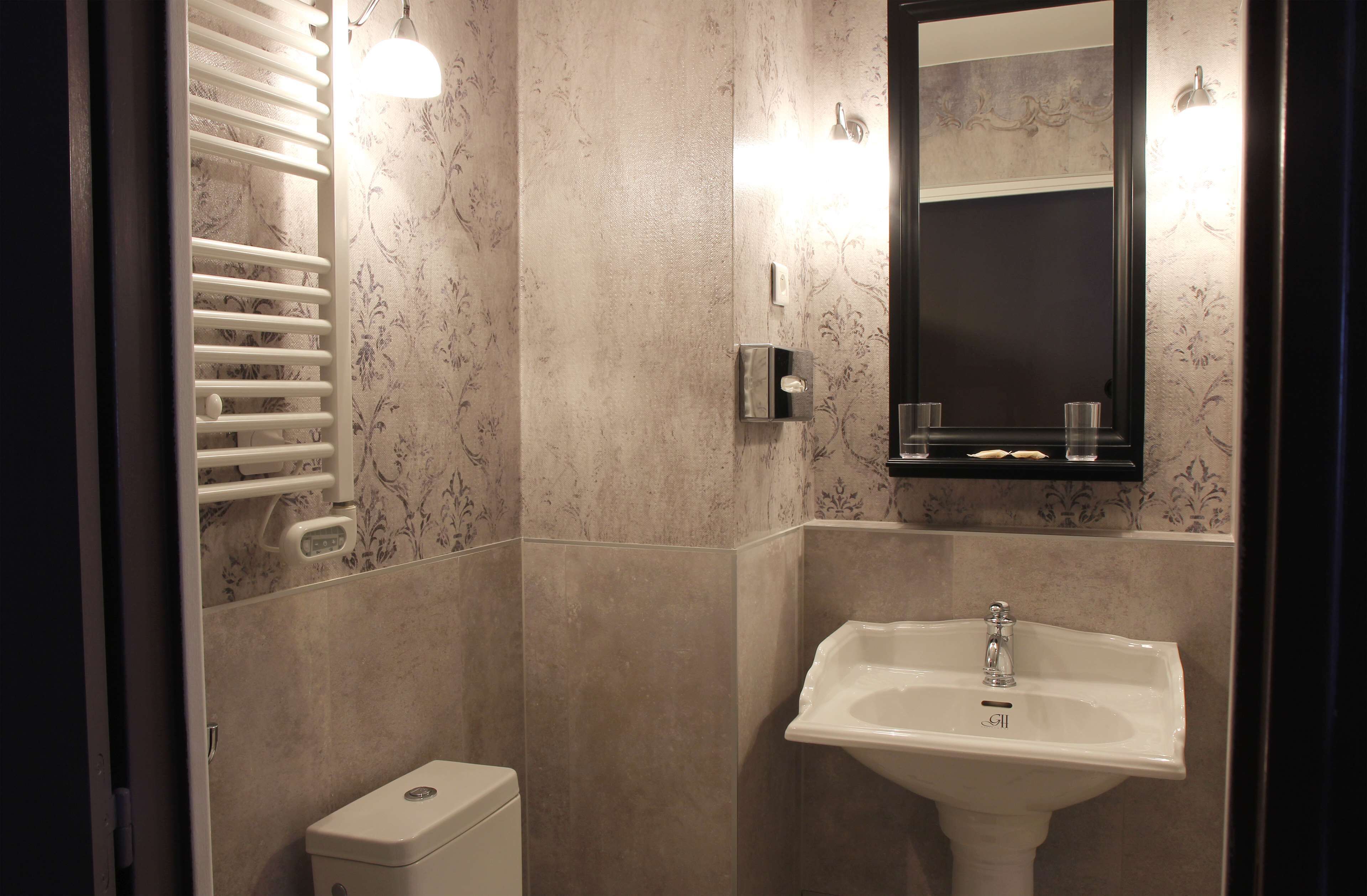 Un baño con un lavamanos blanco, un perchero y un espejo.