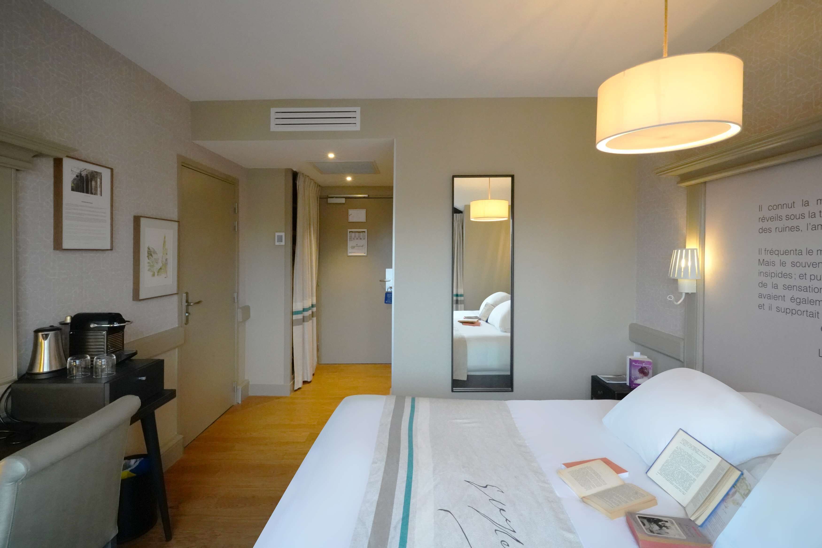Een hotelkamer met een bed, nachtkastje, lamp en spiegel.