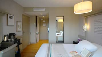 Een hotelkamer met een bed, nachtkastje, lamp en spiegel.