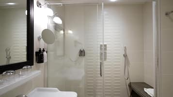 A modern bathroom with a glass-enclosed shower, a large mirror, and a white sink.
