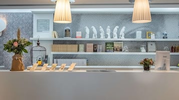 Un área de recepción con un diseño moderno, que incluye una pared con textura, un mostrador de recepción y una variedad de libros y objetos decorativos en estanterías.