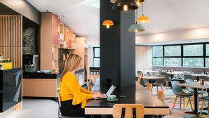 Ein modernes Café mit einer Frau, die an einem Holztisch einen Laptop benutzt.
