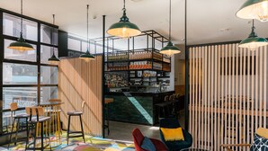 Un espacio moderno de bar con techo alto, paredes de ladrillo visto y diversas opciones de asientos, incluyendo taburetes y sillas.