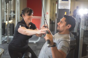 A gym with exercise equipment and a person using a cable machine.