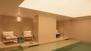 A modern indoor swimming pool with two lounge chairs and a small trash bin. - 9Hotel Chelton (Brussels)