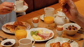 A breakfast setting with plates of food, a teapot, and a cup.