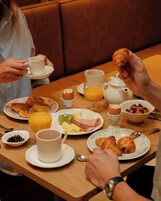 A breakfast setting with plates of food, a teapot, and a cup.