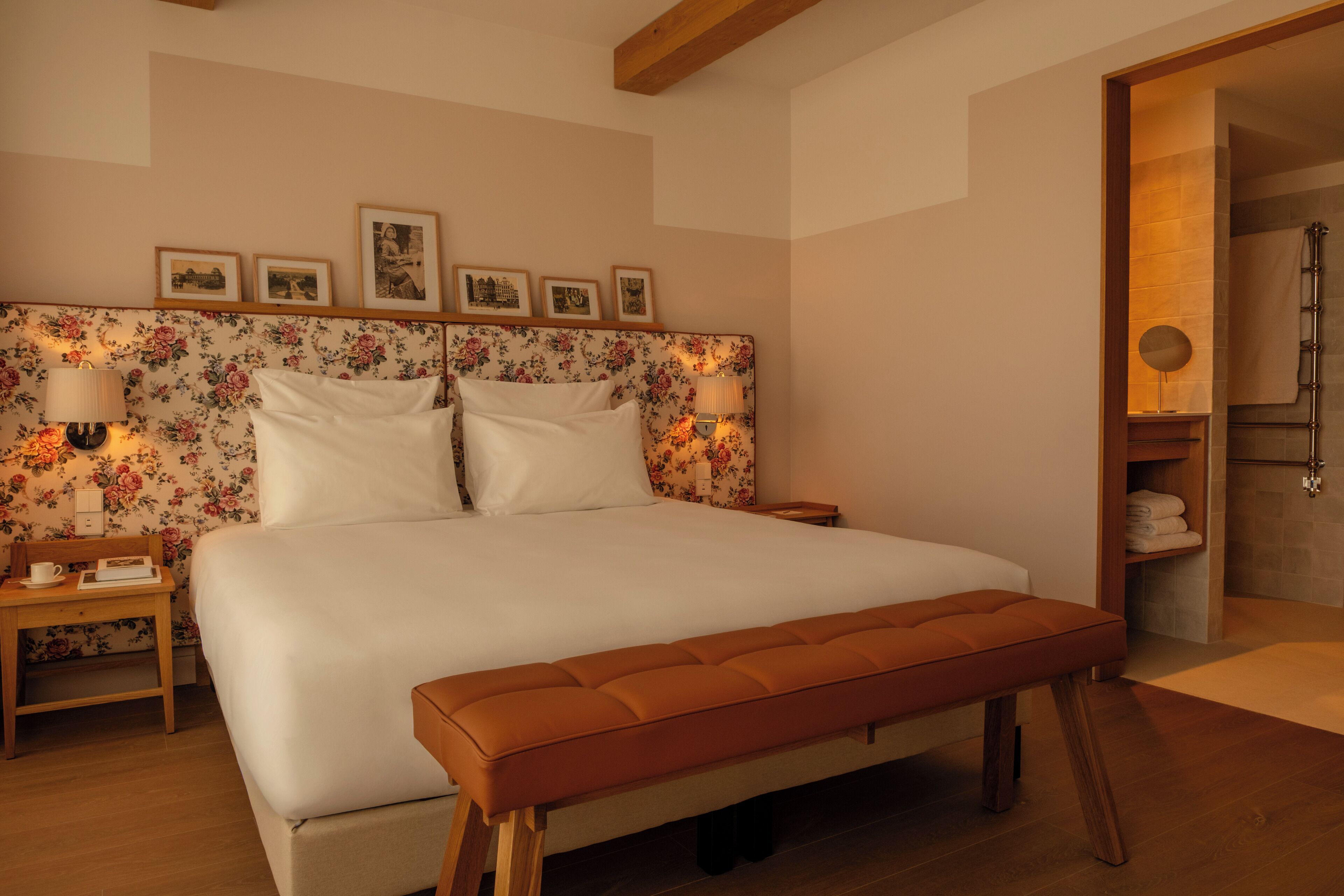A neatly arranged bedroom with a large bed, a bedside table with a lamp, and a bench.