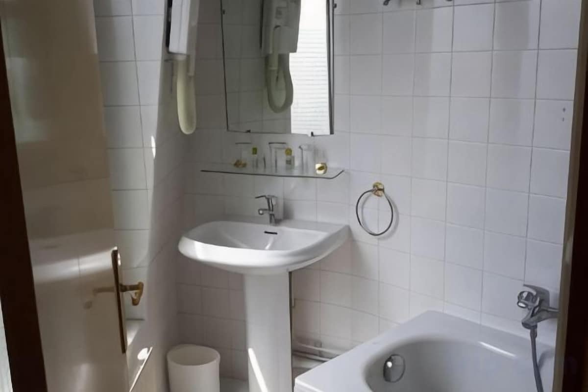 Un baño con un lavamanos blanco, un espejo, una bañera y un inodoro.
